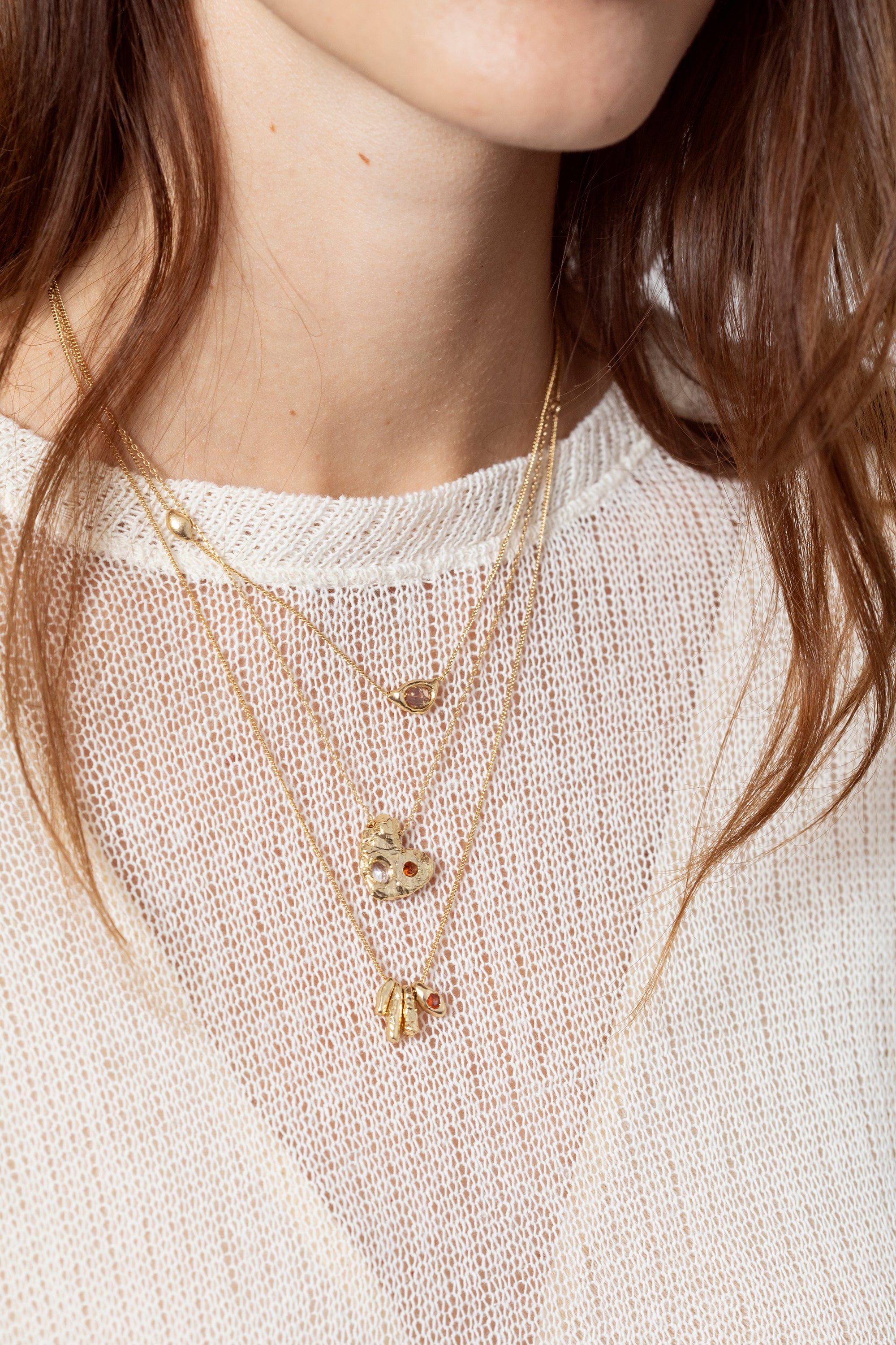 Model styling sculptural gold gemstone pendant necklace in layered jewelry look
