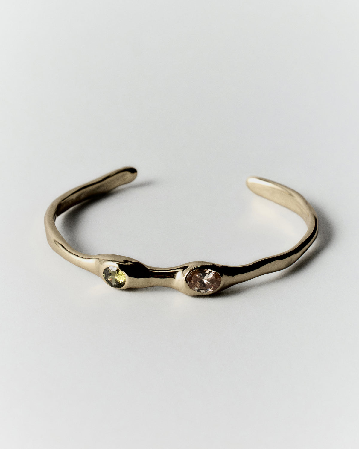 Ambar Bracelet in gold: open slender cuff bracelet with two small contrasting stones.