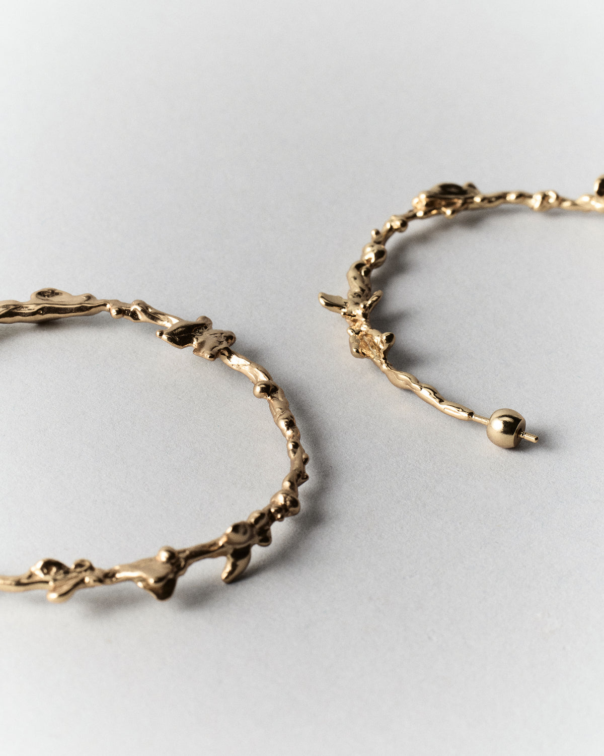Butterflies Dance Hoops in gold: close-up of the hoops' textured edges and rounded ends.