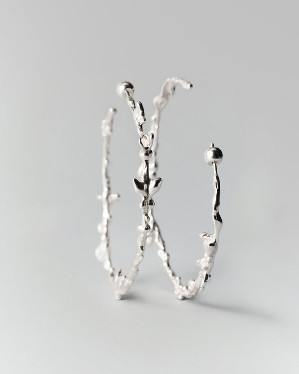 Butterflies Dance Hoops in silver: hoop earrings standing upright to show their irregular profiles.