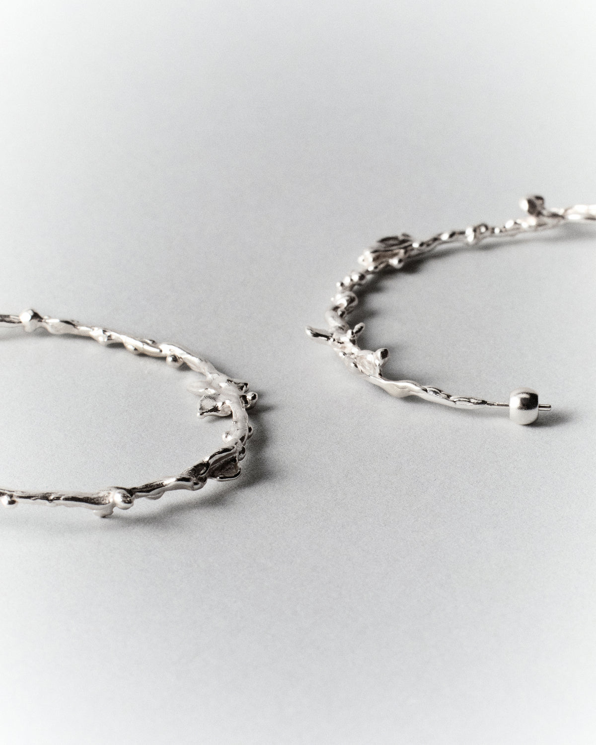 Butterflies Dance Hoops in silver: close-up of the hoops' textured edges and rounded ends.