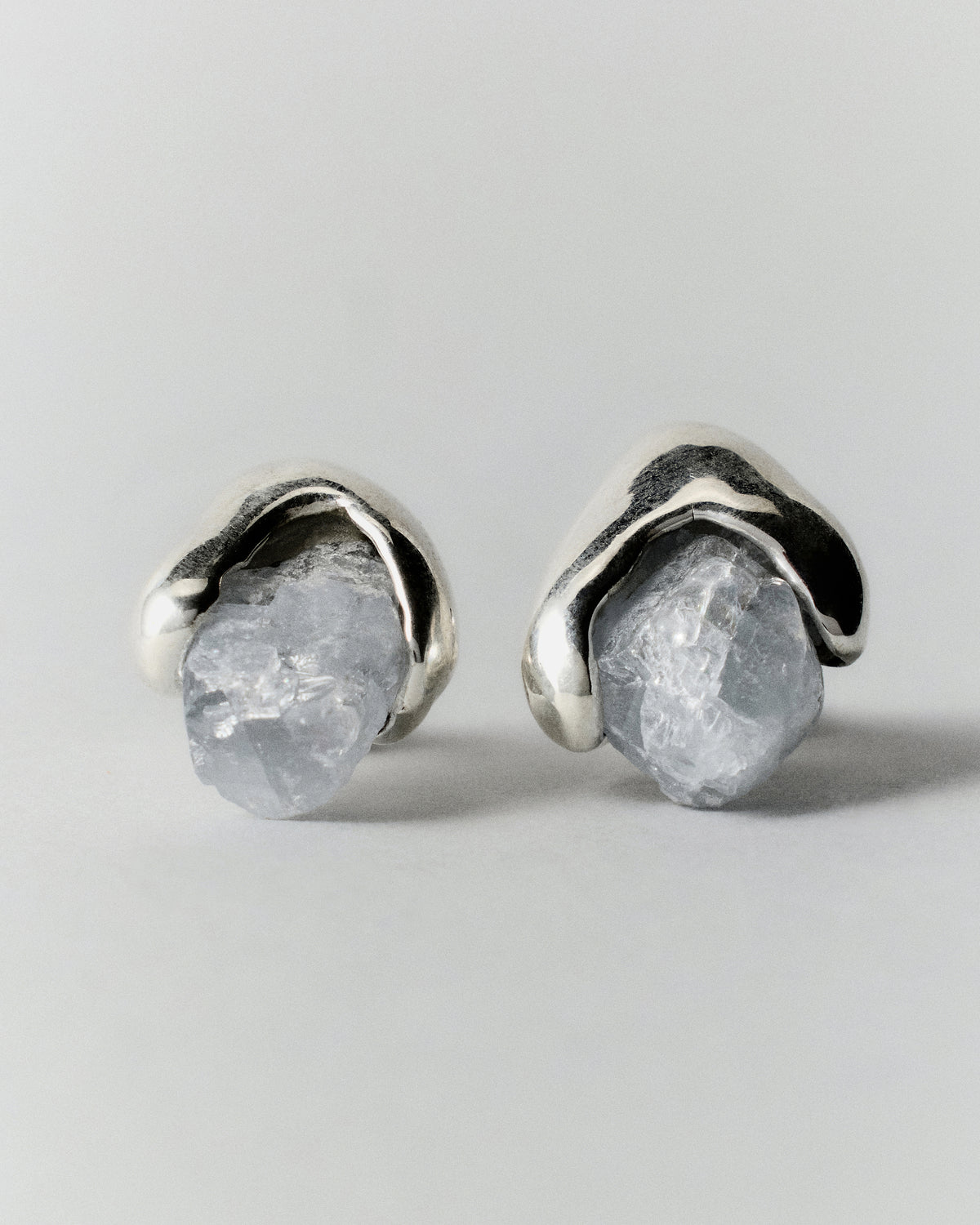 Celestite Earrings in silver: pair of pale blue rough-stone stud earrings on a light background.