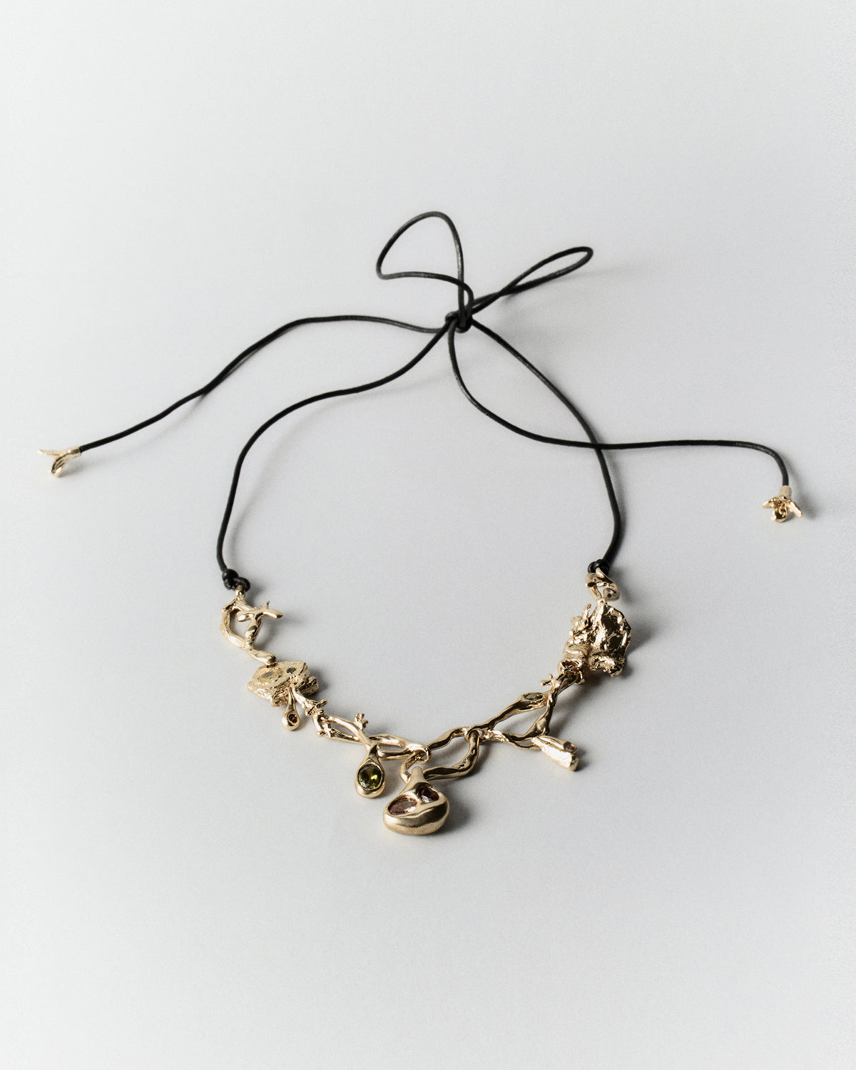 Cocoon Necklace in gold: necklace with irregular linked charms and black tie cord.