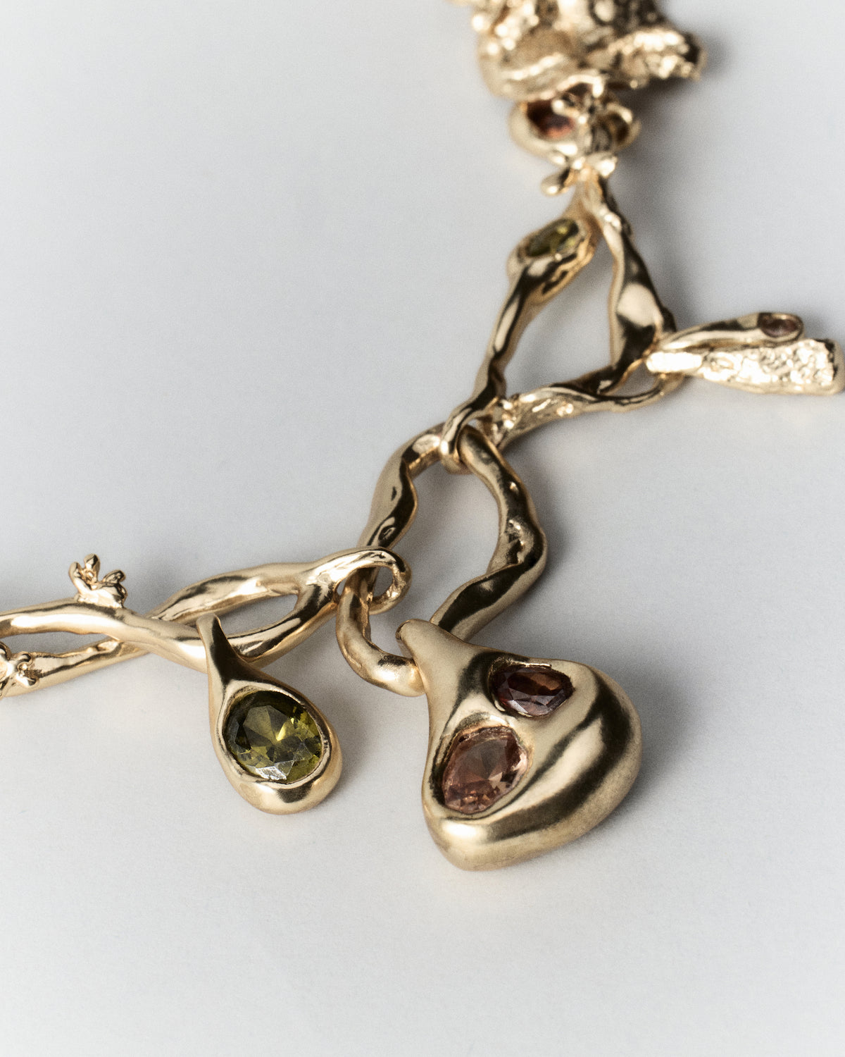 Cocoon Necklace in gold: close-up of the necklace's irregular links and rounded charms.