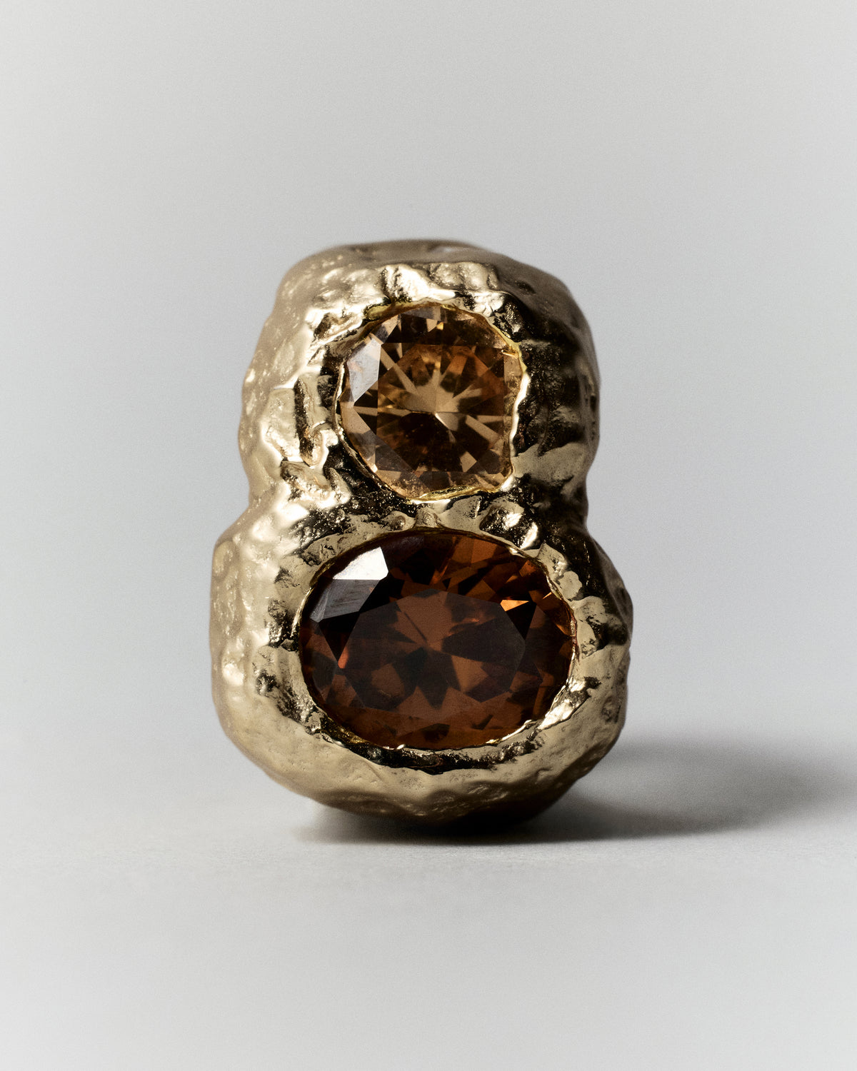 Cocoon Ring in gold: wide textured ring with a large amber-colored stone and smaller accents.