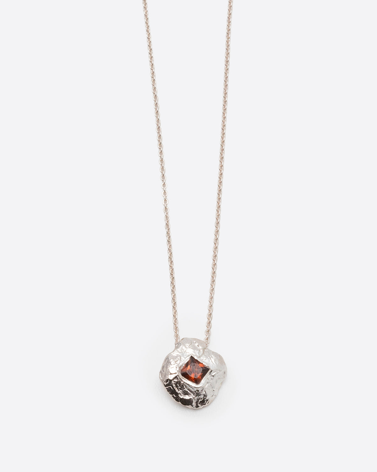 Helios Necklace in silver: pendant and fine chain shown together on white.