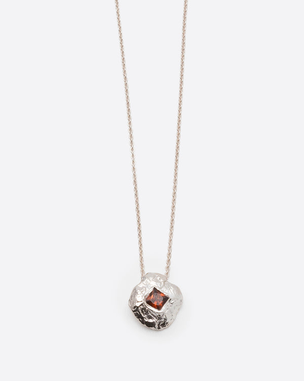Helios Necklace in silver: pendant and fine chain shown together on white.