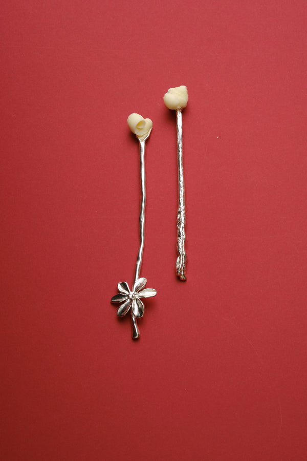 Set of sculptural silver spoons with organic floral design and butter detail on red background