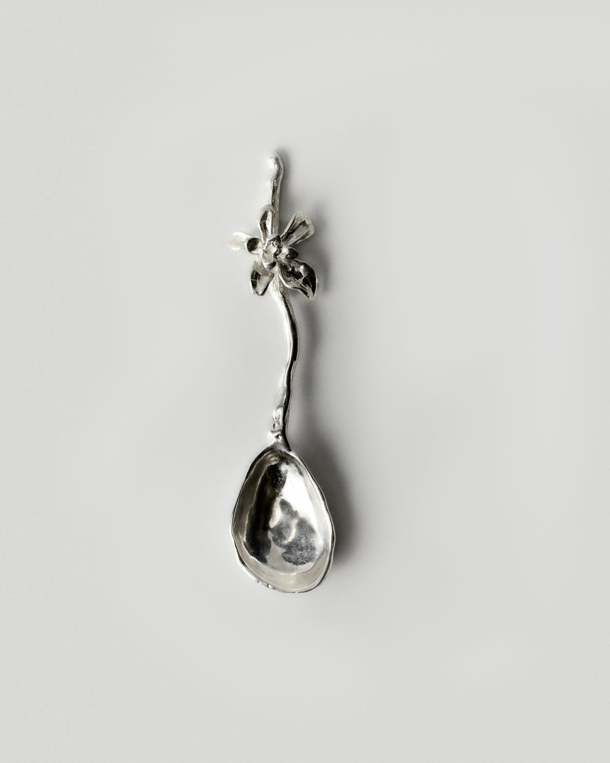 Iris Bloom Cutlery Spoon, Stirring Stick in silver: full view of the flower-handled spoon on a pale background.