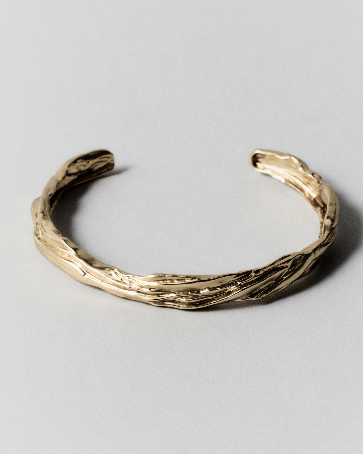 Layered Earth Cuff in gold: open slender cuff with flowing textured surface.