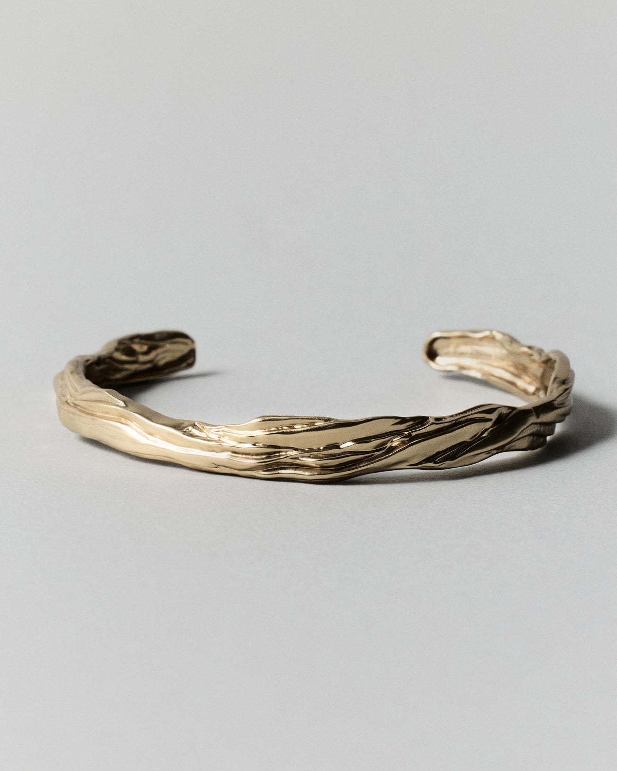Layered Earth Cuff in gold: low angled view of the open cuff and its raised edges.