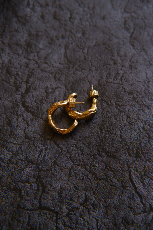 Layered Earth Hoop Earrings in gold: hoop earrings styled on a dark textured surface.