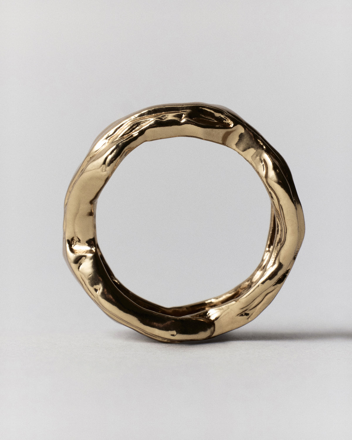 Layered Earth Ring in gold: ring standing upright showing its irregular textured circular band.