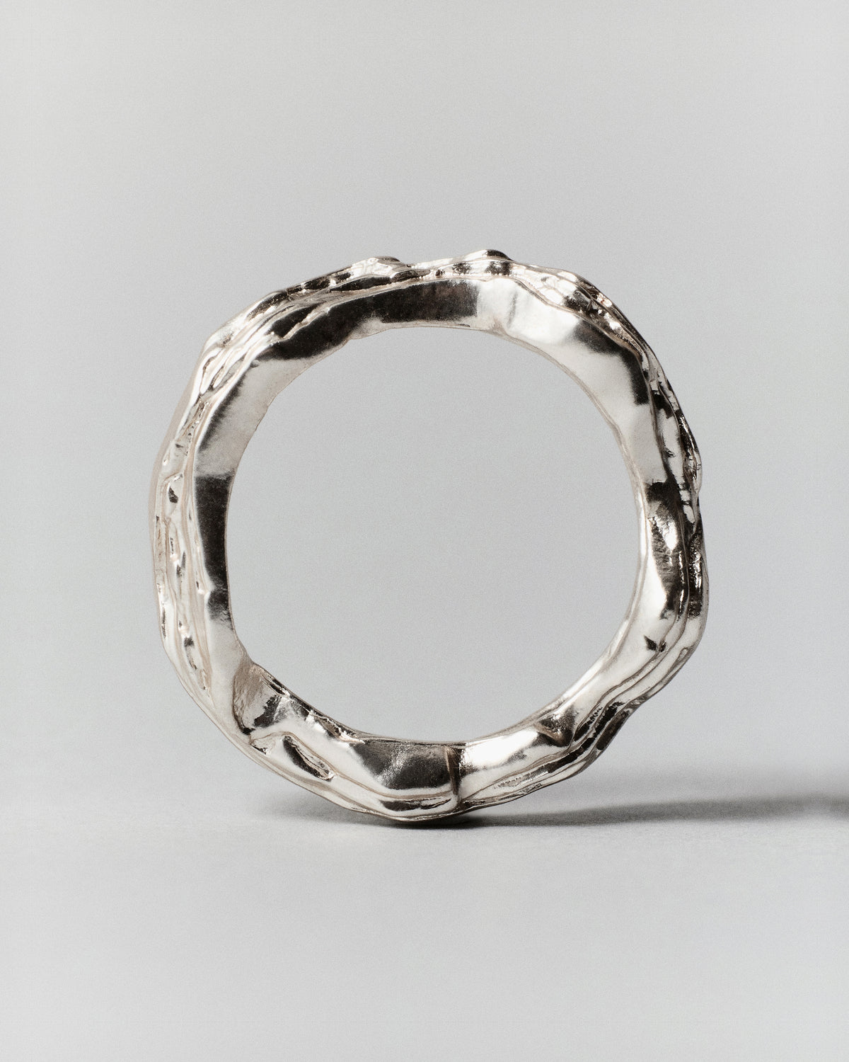 Layered Earth Ring in silver: ring standing upright showing its irregular textured circular band.
