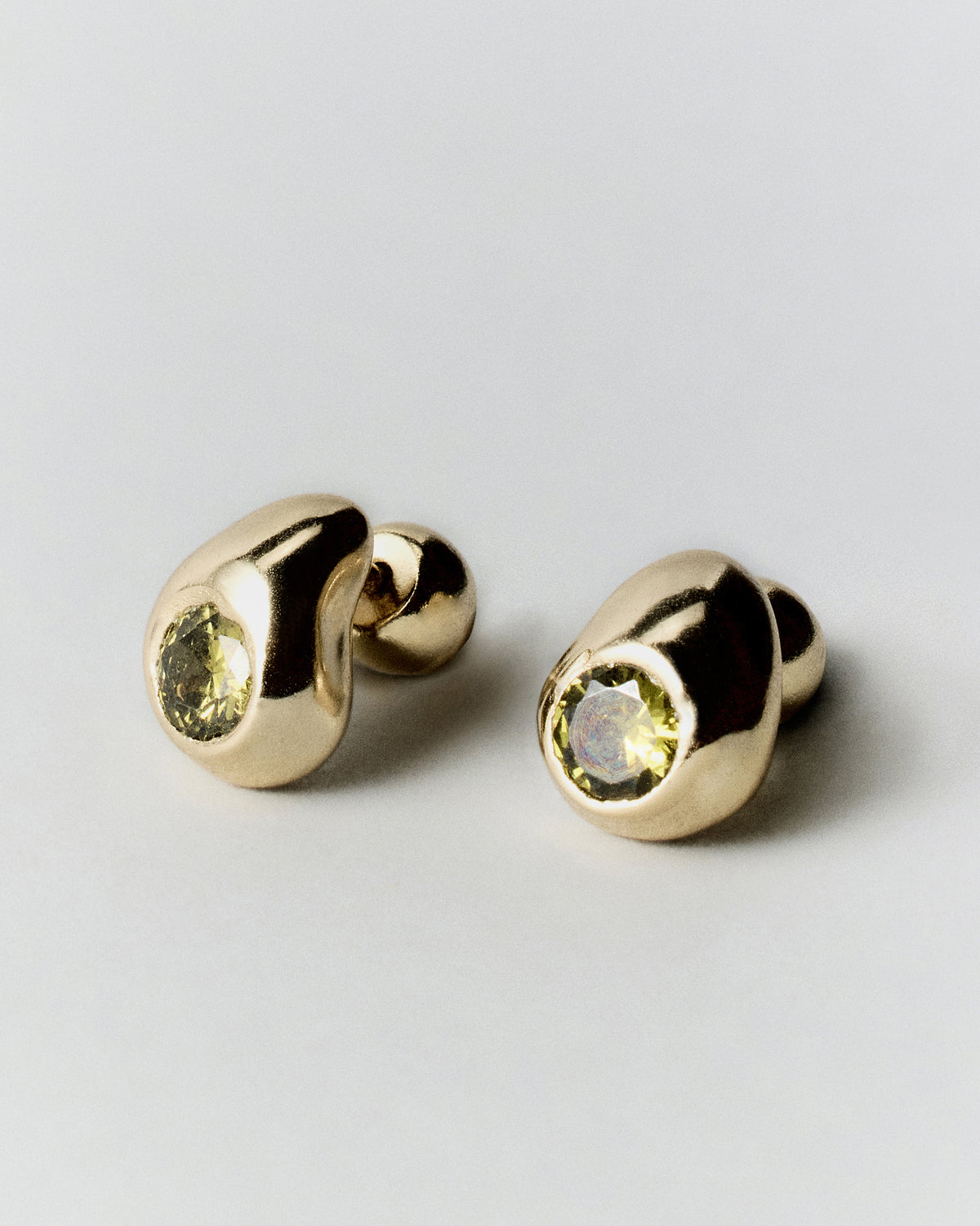 Pepita Studs Earrings in gold: angled view of rounded green-stone stud earrings.