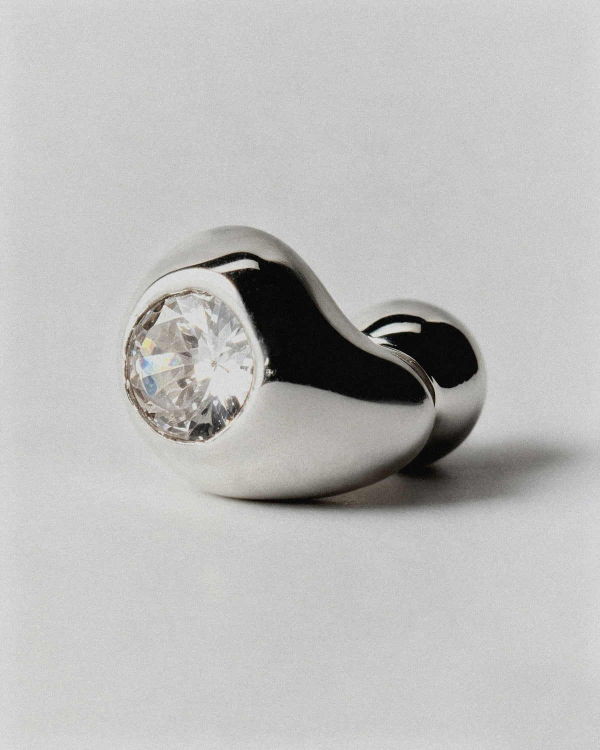 Pepita Studs Earrings in silver: side view of a rounded stud earring and its pale stone.