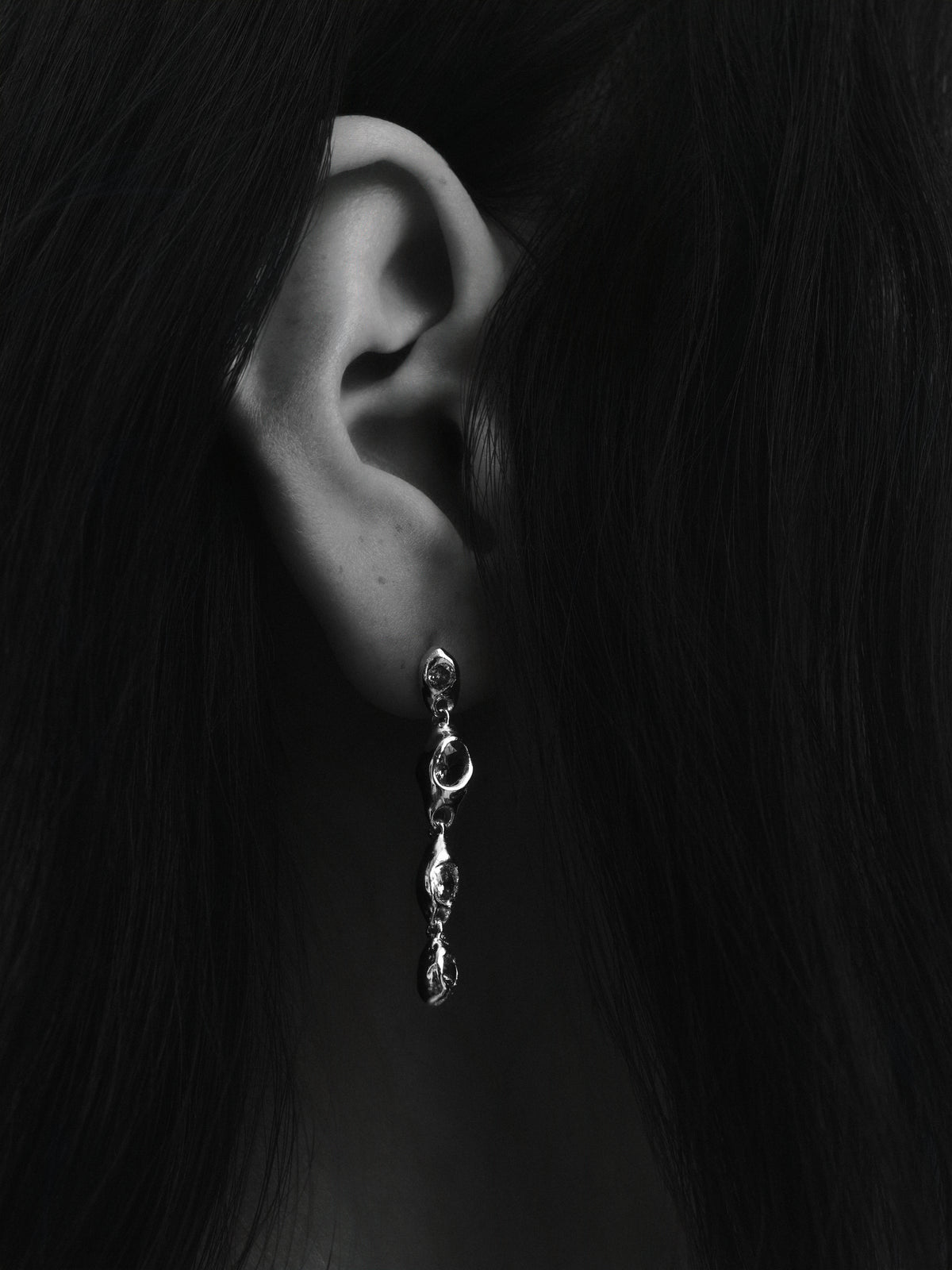Prado Pepita Long Earrings in silver: black-and-white close-up of a model wearing a long dangling earring.
