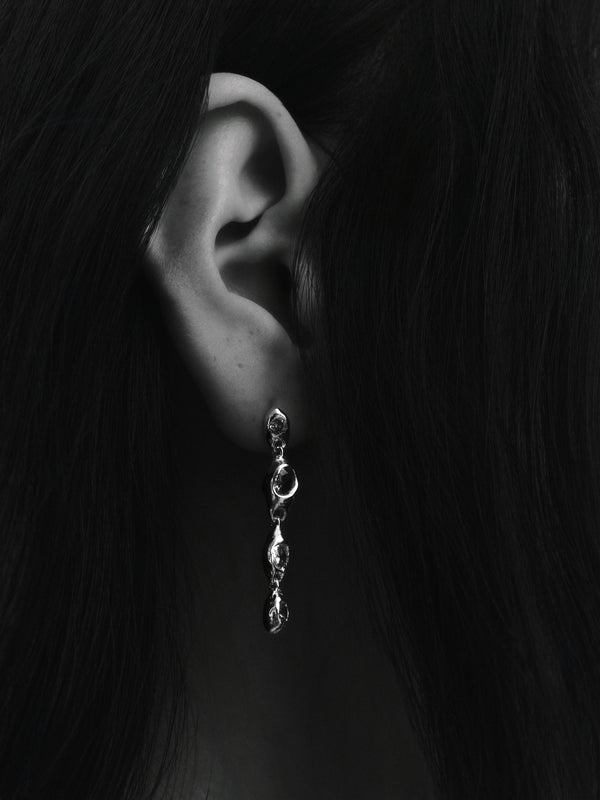 Prado Pepita Long Earrings in silver: black-and-white close-up of a model wearing a long dangling earring.