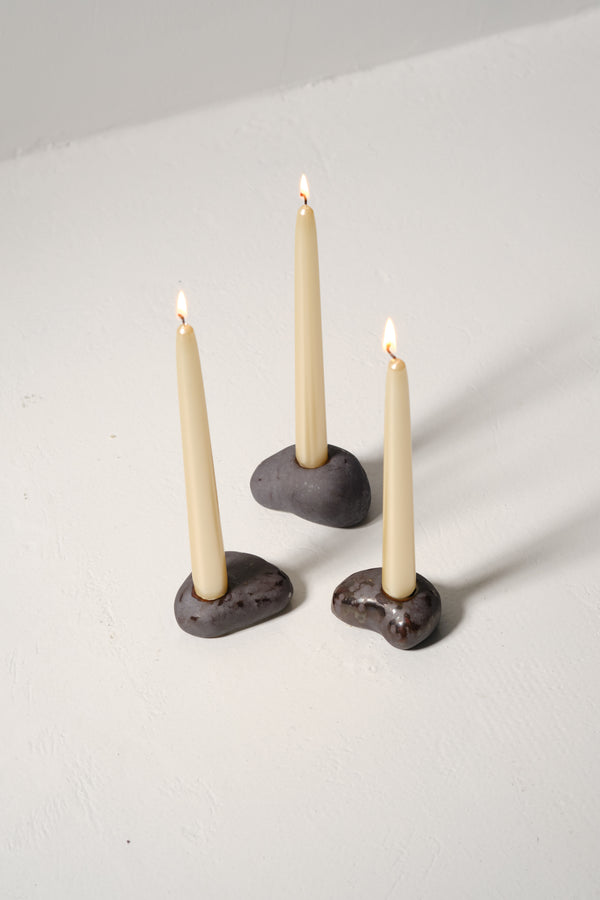 River stone Ceramic Candle Holder: three pebble-shaped holders with lit taper candles.
