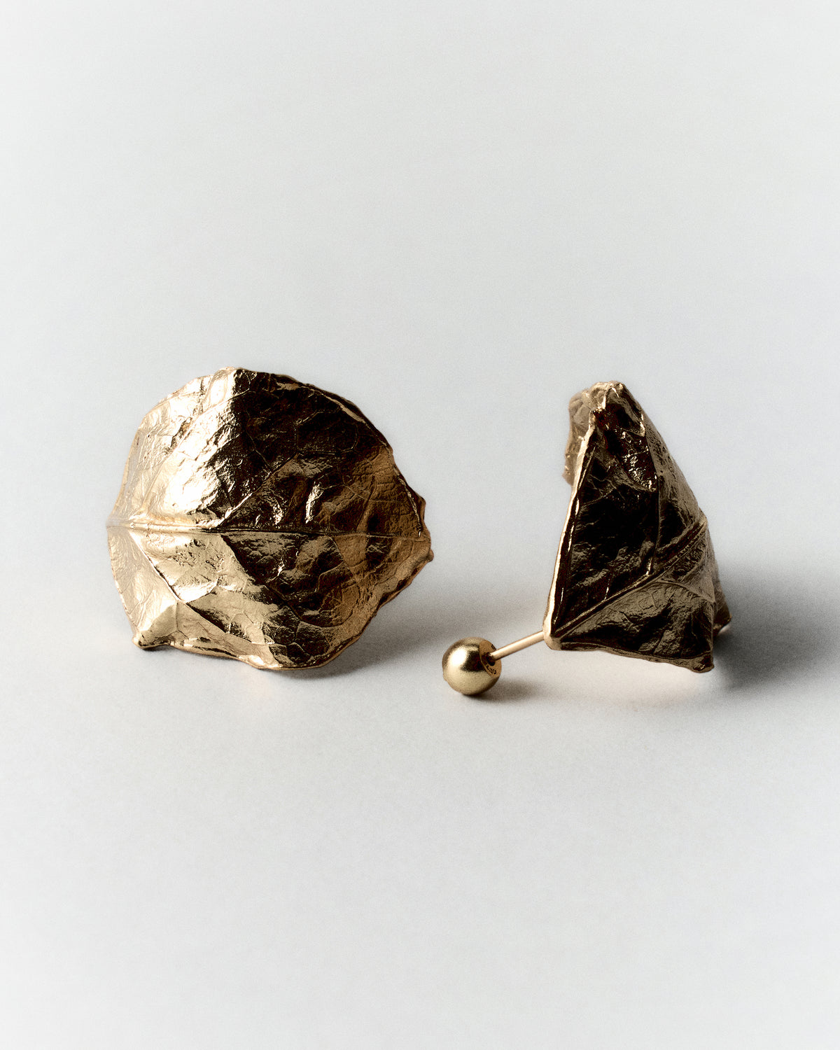 Small Vitalis Earrings in gold: pair of small sculptural earrings with folded textured surfaces.