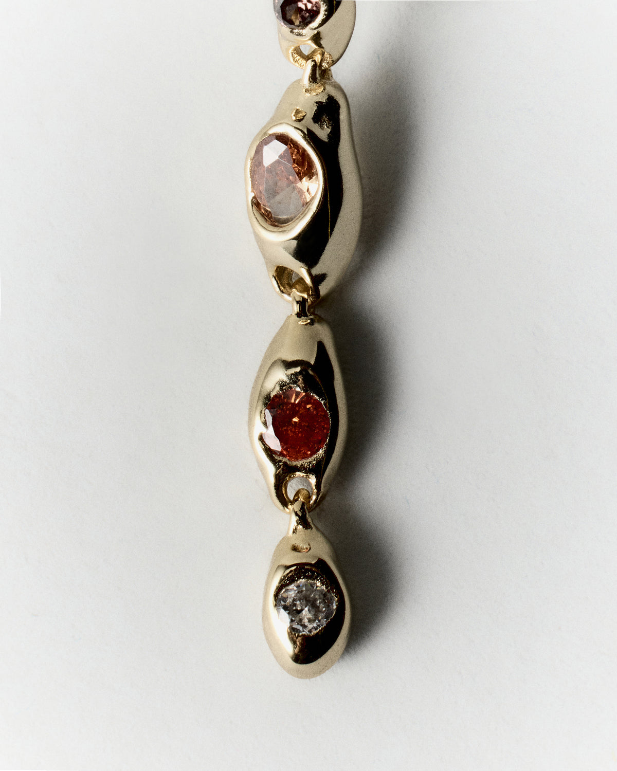 Sunset Pepita Long Earrings in gold: close-up of linked rounded stone settings along a long earring.