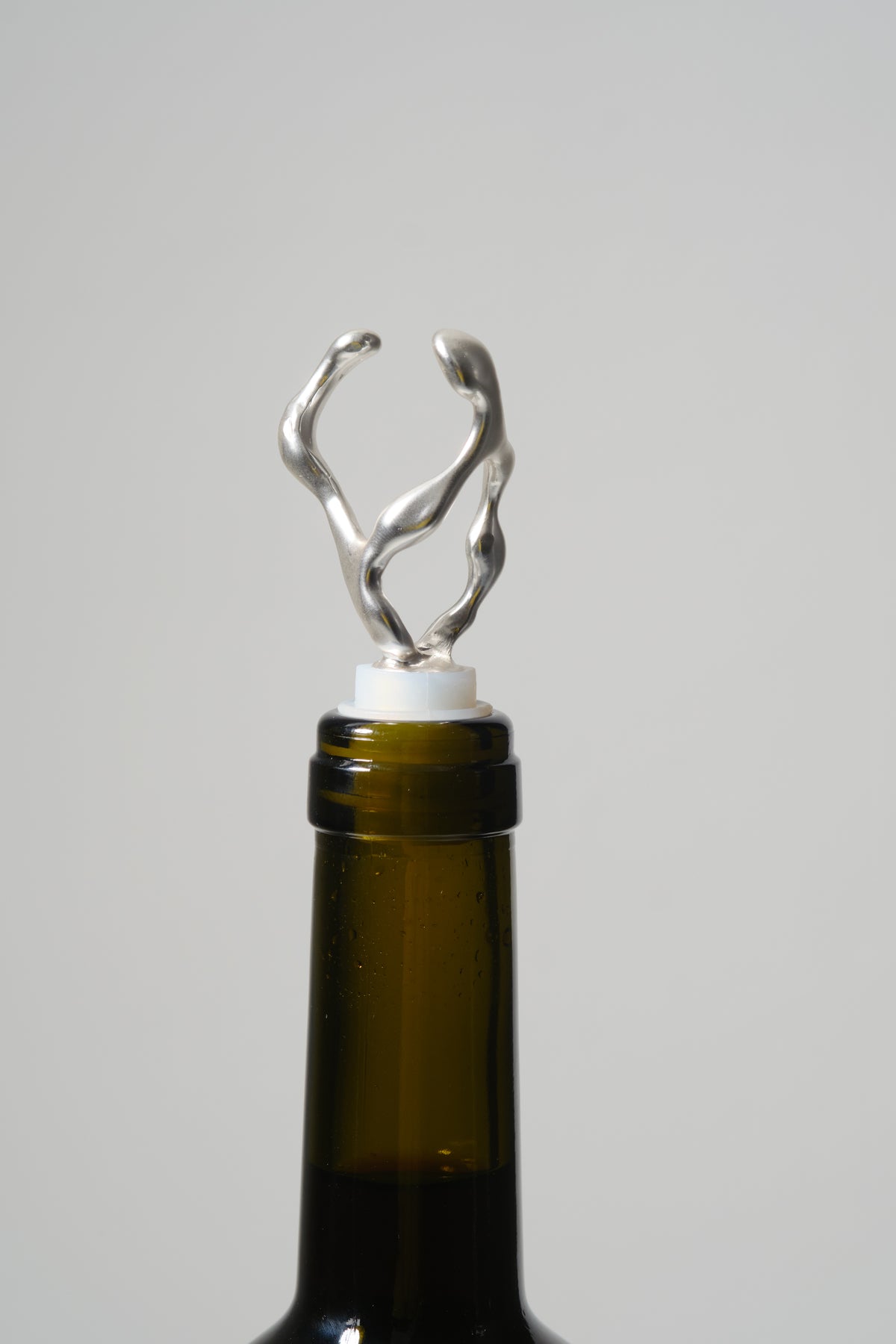 Sway Metal Wine Cork in silver: openwork wine stopper fitted into a dark bottle.
