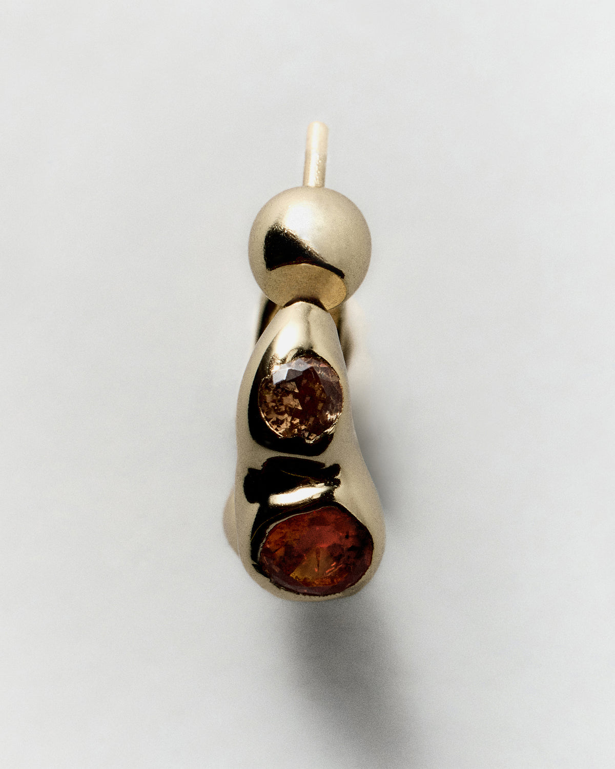 Tonka Hoops in gold: close-up of a hoop showing two reddish inset stones.