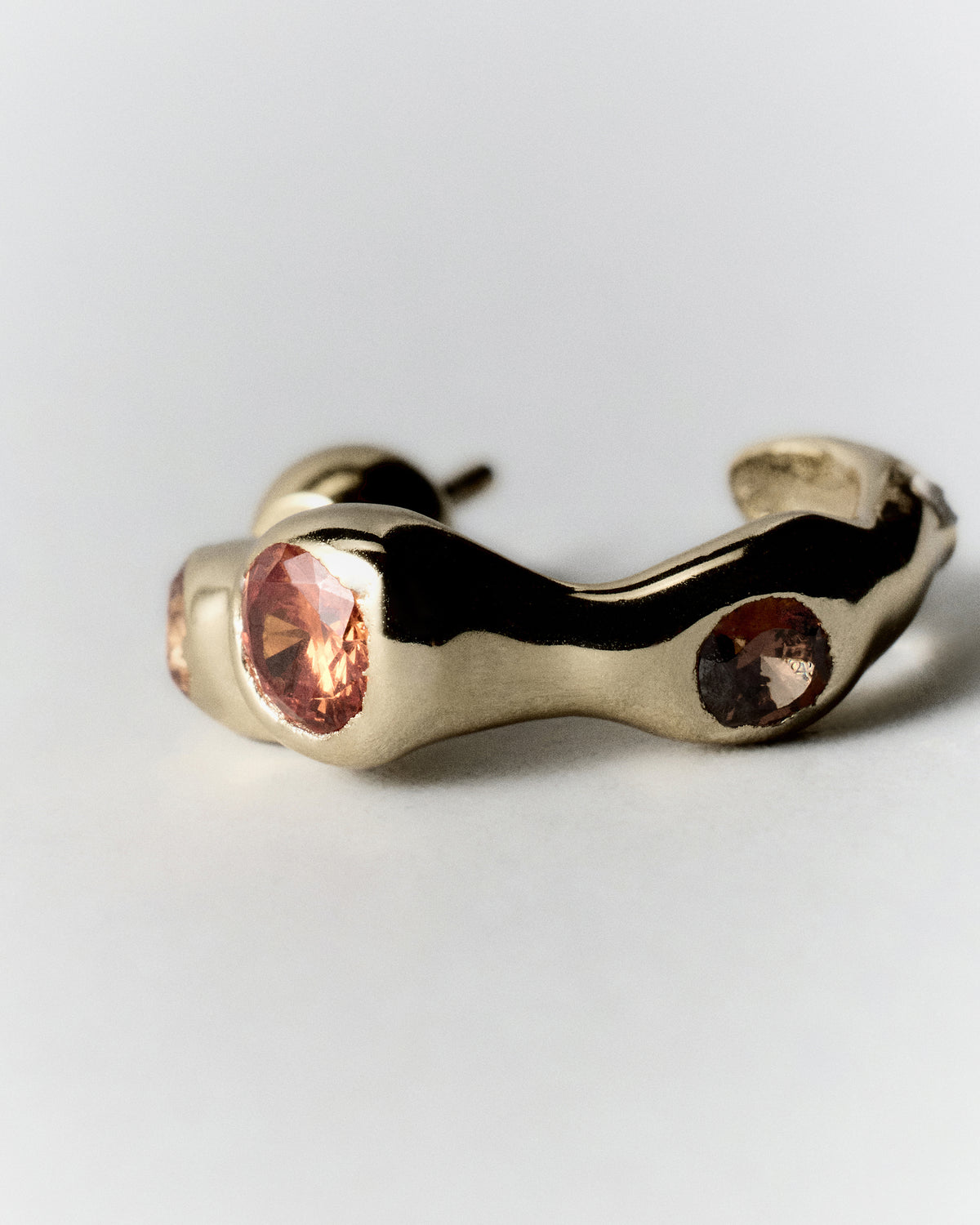 Tonka Hoops in gold: hoop laid on its side showing the open curve and inset stones.