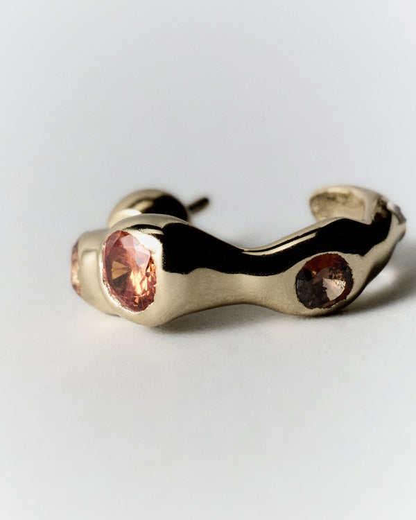 Tonka Hoops in gold: hoop laid on its side showing the open curve and inset stones.