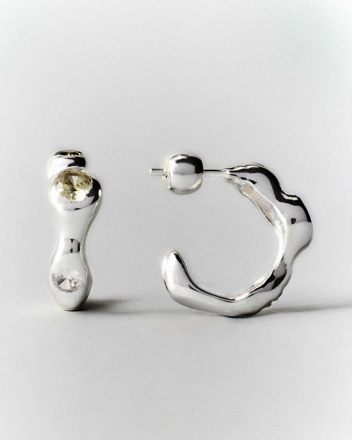 Tonka Hoops in silver: front and side views of a pair of hoops with pale green stones.