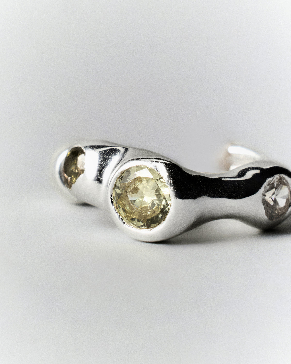 Tonka Hoops in silver: hoop laid on its side showing the open curve and inset stones.