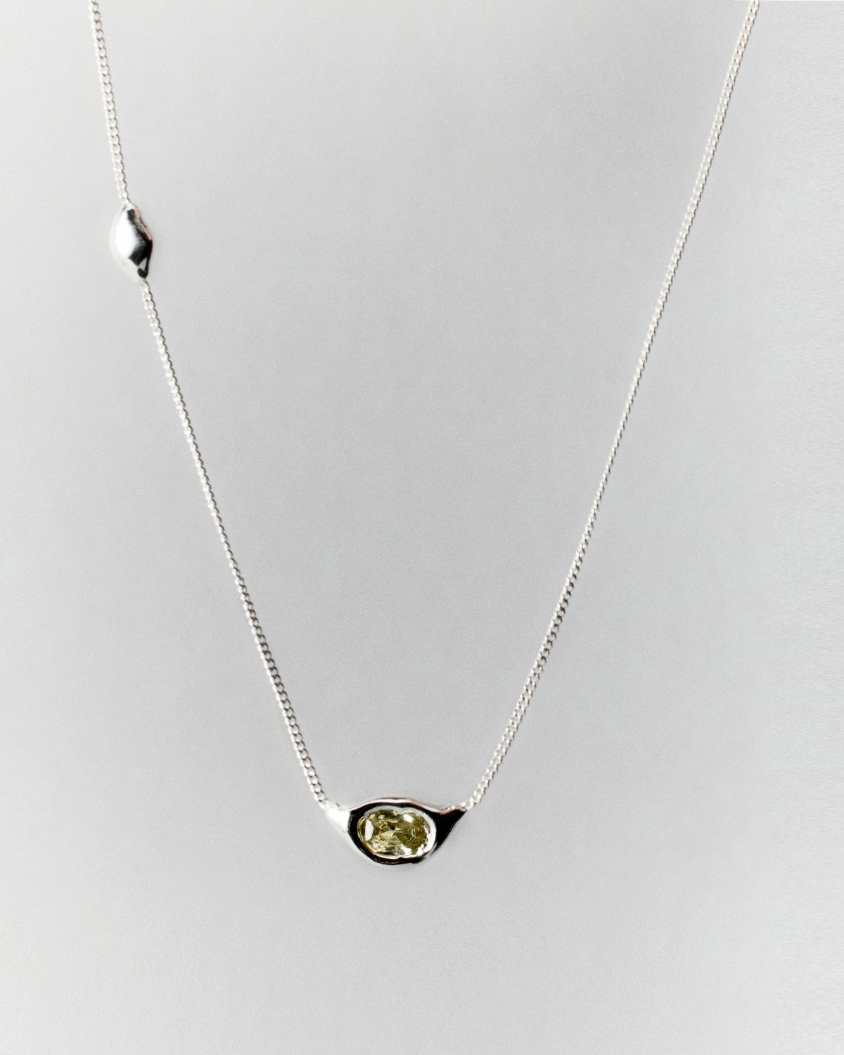 Tonka Necklace in silver: fine-chain necklace with an oval yellow-green central stone.