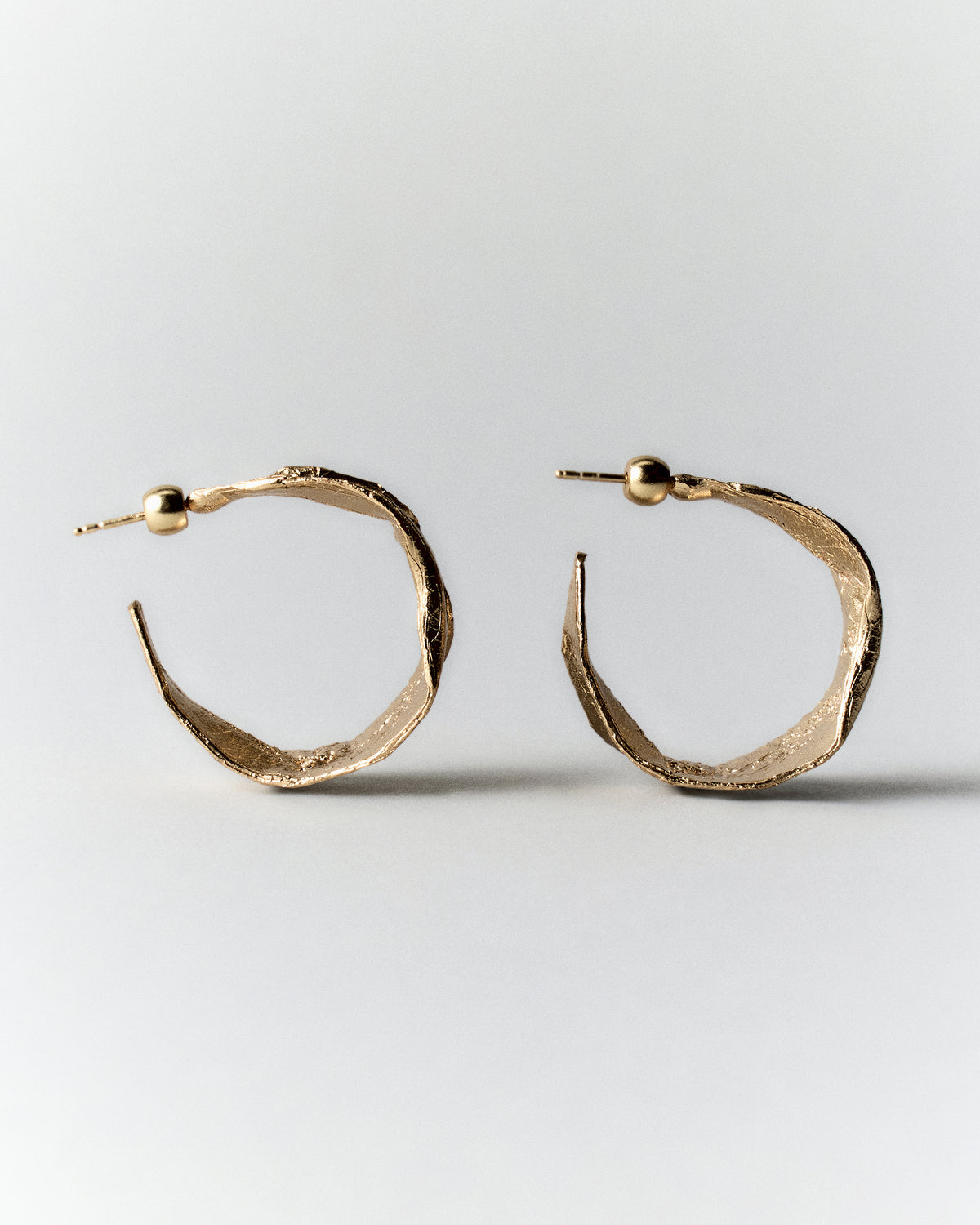 Vitalis II Hoops in gold: pair of broad open hoop earrings shown from the side.