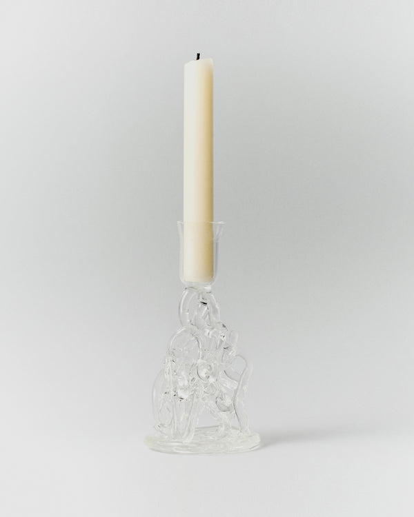 Watercousre Glass Candle Holder: clear sculptural glass candle holder with a lit taper candle.