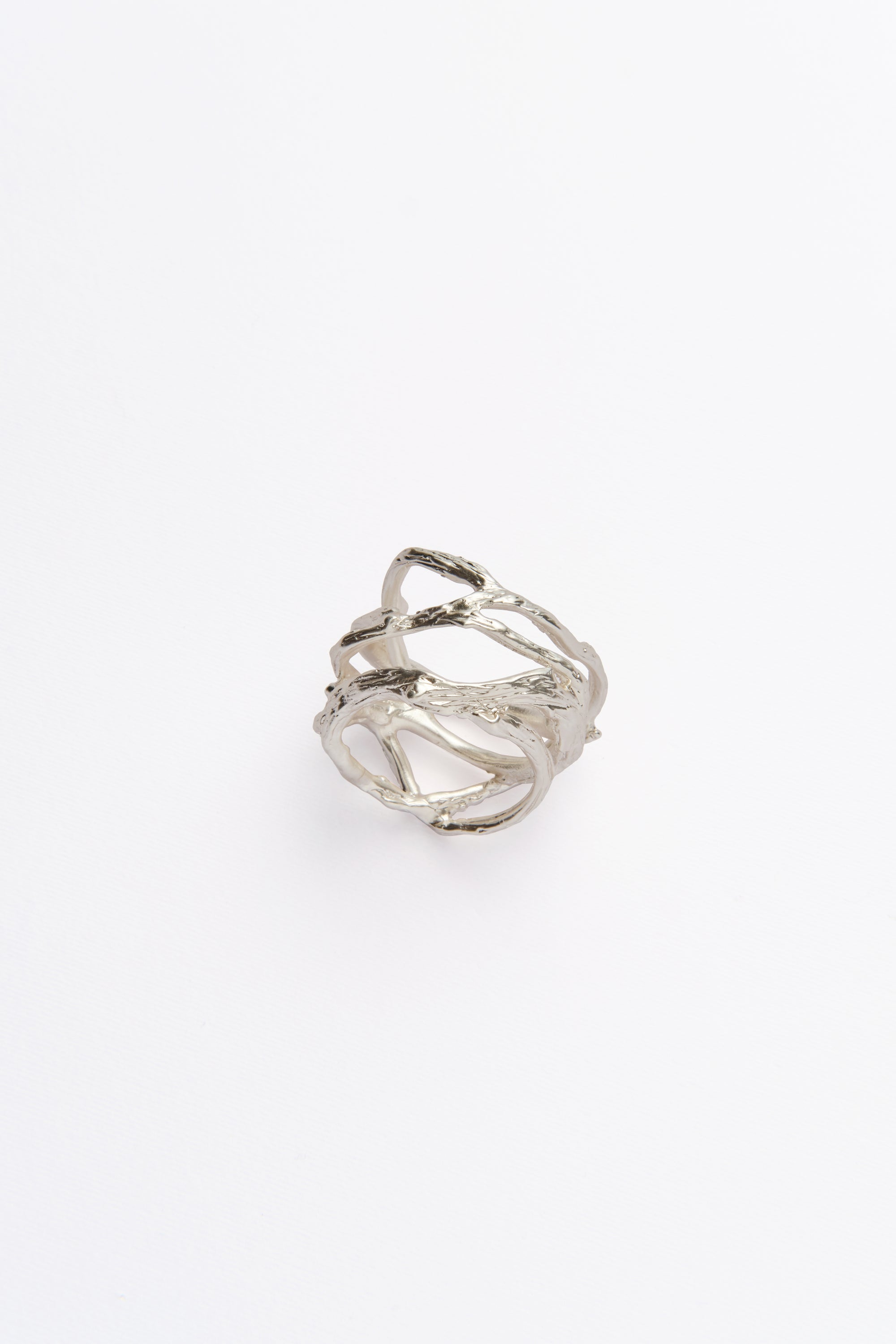 A single silver napkin ring with an organic texture displayed on a green background.