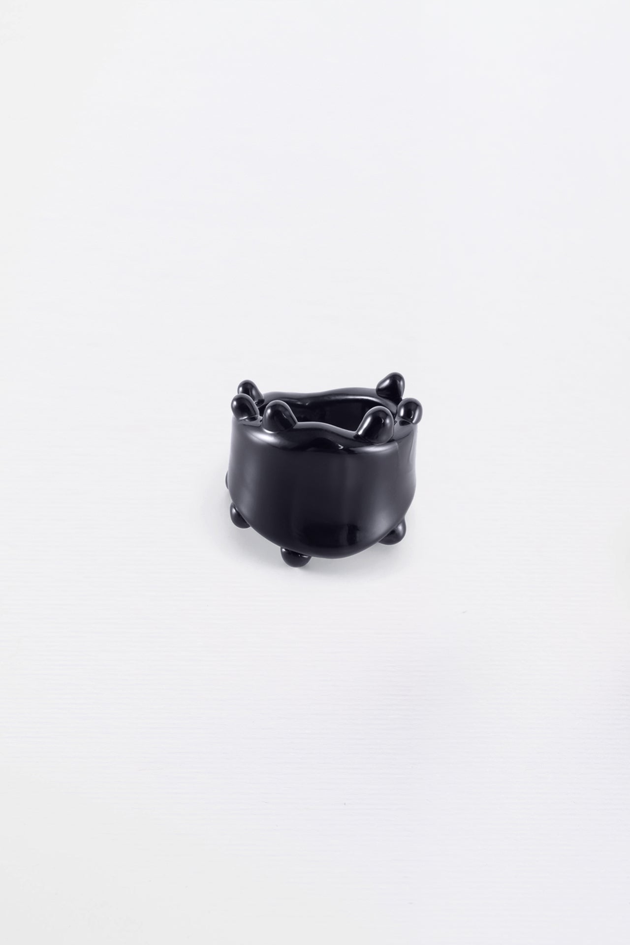A black glass ring with a smooth, curved design, displayed against a white background.
