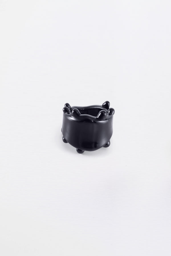 A black glass ring with a smooth, curved design, displayed against a white background.