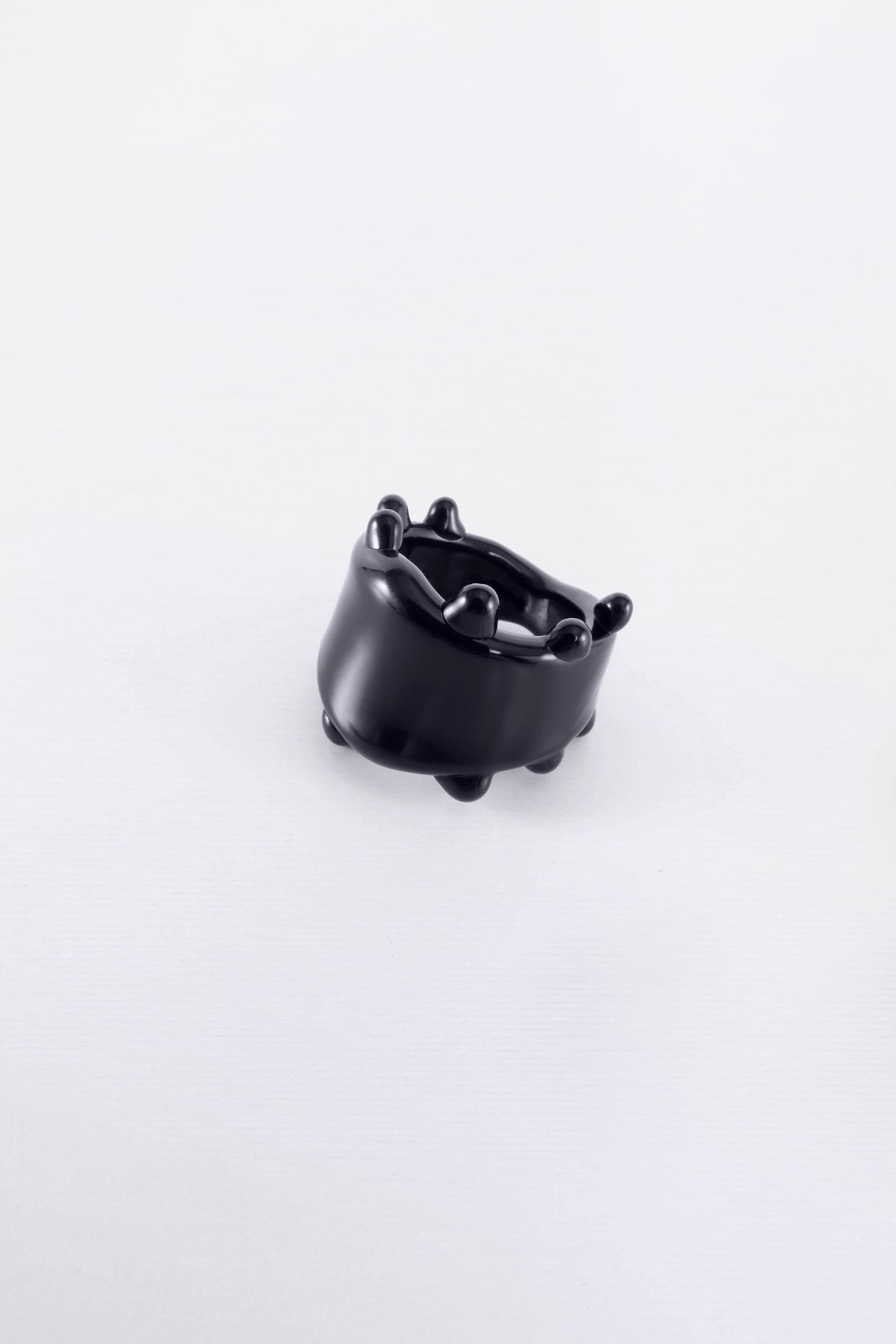 A black glass ring with a smooth, curved design, displayed against a white background.