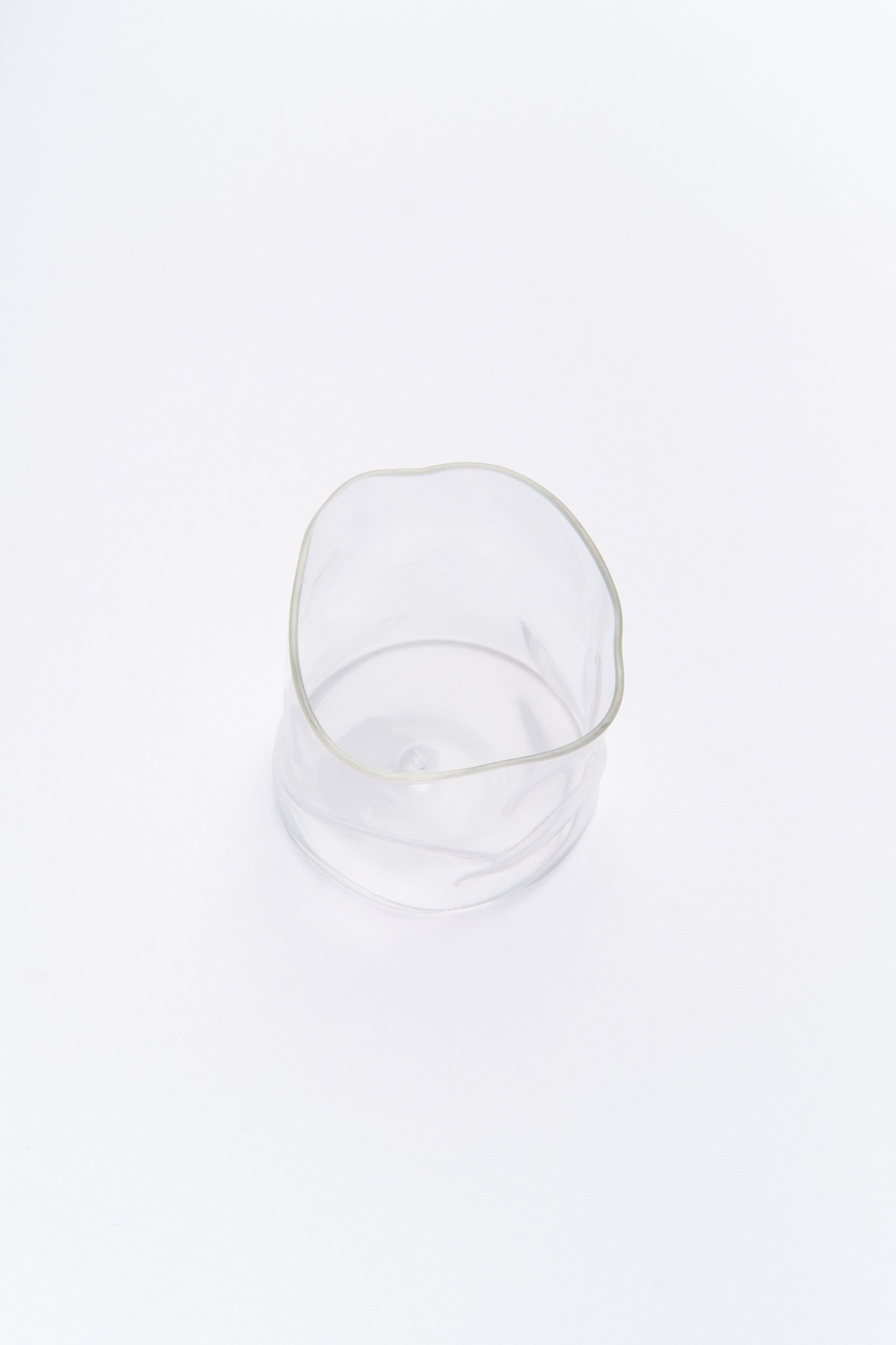 A clear glass with organic, curved shape, gently reflecting light on its surface.