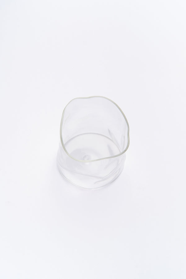 A clear glass with organic, curved shape, gently reflecting light on its surface.