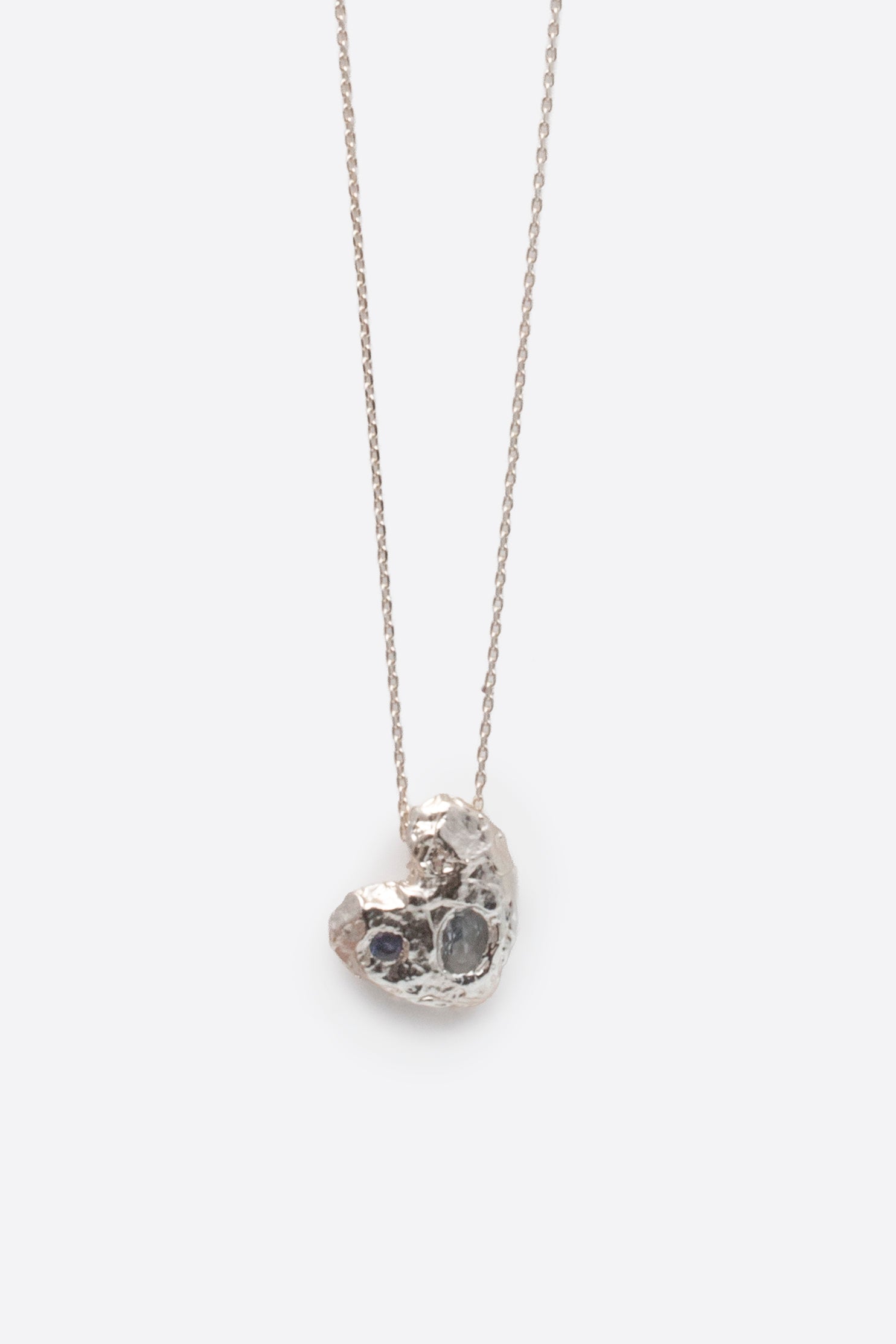 Close-up of silver textured solid heart pendant with two stones