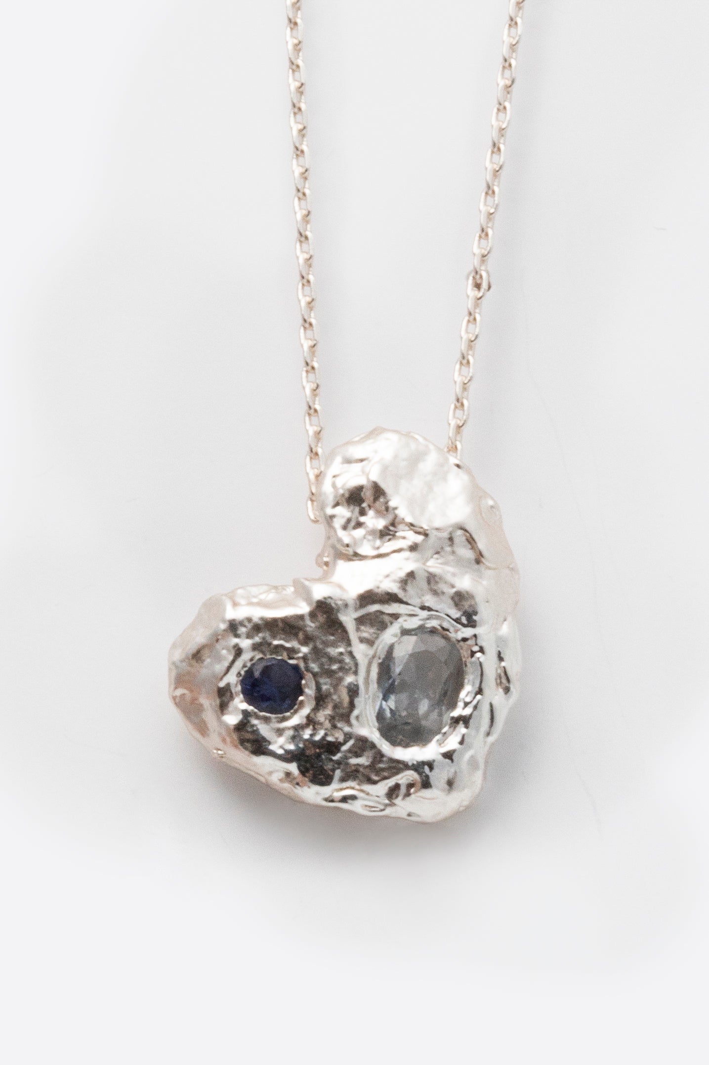 Detail of silver hammered heart pendant with two stones